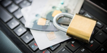 Padlock and stack of credit cards on top of laptop